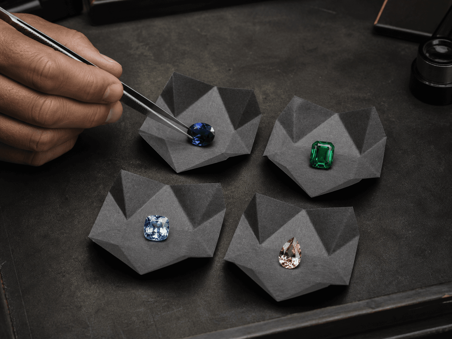 A jeweller selecting from four loose gemstones
